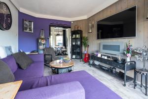 希佛萨姆Beautiful house n.Amsterdam, suitable for families的客厅配有紫色沙发和电视
