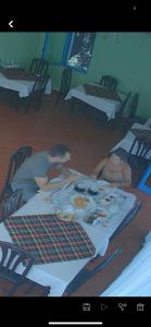 伏罗拉Hotel Dini的两个人坐在桌子上,一边吃着食物