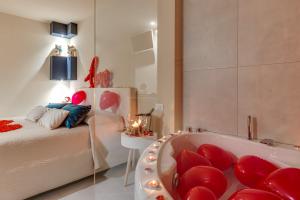 夏卡!!! IDROMASSAGGIO !!! - Love Suite的一间卧室配有一张床和一个配有红色椅子的浴缸