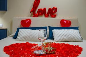 夏卡!!! IDROMASSAGGIO !!! - Love Suite的一张红玫瑰床和一杯葡萄酒