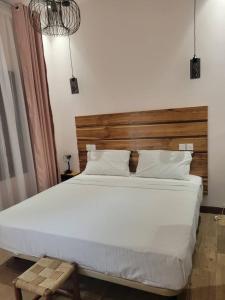 博博迪乌拉Villa Soudan的卧室配有一张白色大床和木制床头板
