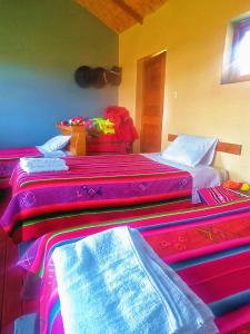 普诺TITICACA'S SALA UTA的一间设有三张床的客房,床上配有色彩缤纷的毯子