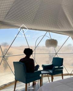 瓦迪拉姆Rum Mars luxury camp的坐在椅子上,从窗户望出去的女人