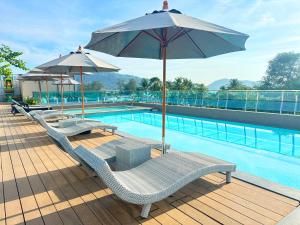 芭东海滩Clarian Hotel Beach Patong的一个带2把躺椅和遮阳伞的游泳池