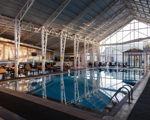 奥什Jannat Resort Osh的大楼内带桌椅的大型游泳池