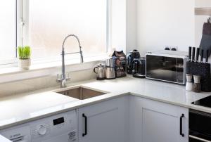 纽波特Stylish Duplex Apartment with Home Office的白色的厨房配有水槽和微波炉