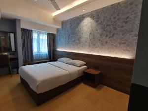 卢穆特Lumut Hotel的一间卧室设有一张床和石墙