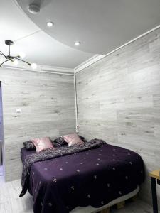 基希讷乌Apartment的一间卧室配有一张带木墙的紫色床