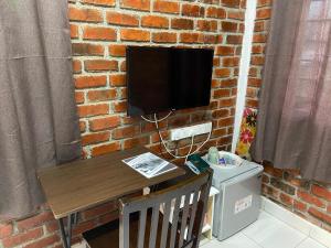 巴东勿刹Padang Besar Green Inn的挂在砖墙上的电视,带有桌子和桌布的立体性关节炎