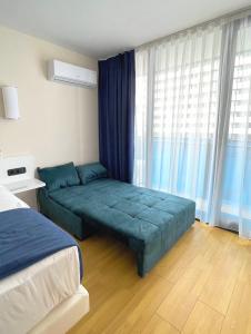 巴统Apartments Black Sea Resort的一间卧室配有一张带蓝色床单的床和一扇窗户。