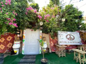 卢克索peace garden hostel & camp的一座花园,花园内设有白色的门,并种植了粉红色的鲜花