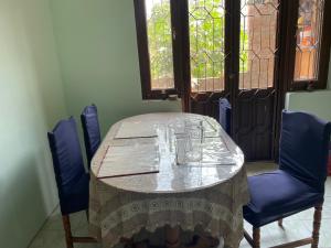 帕坦Kasaa home的一张桌子,两把蓝色的椅子,一张桌子,一张桌子,一张布