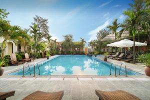 宁平Dong Ne Tam Coc Hotel & Resort的一个带椅子和遮阳伞的度假村游泳池