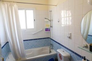 帕福斯Sunset Green 01的蓝色和白色的浴室设有浴缸和窗户。