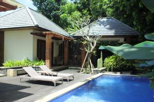 MungguBelvilla 93903 Pandawa Sharing Villa Riverside的后院设有游泳池、椅子和房屋