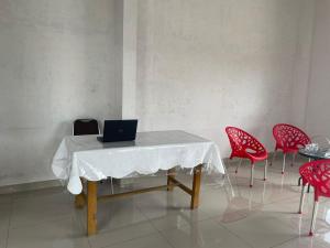 棉兰OYO 93947 Bahagia Guest House的一张桌子,上面有笔记本电脑和红色椅子