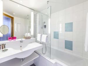 弗赖辛诺富特慕尼黑机场酒店的白色的浴室设有水槽和淋浴。