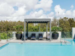 布里斯班布里斯班机场普尔曼酒店的游泳池旁设有椅子和凉亭