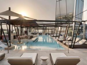 迪拜SO/ Uptown Dubai的一座带躺椅的建筑的顶部游泳池