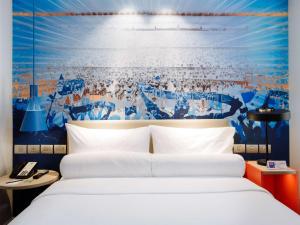 马尼拉ibis Styles Manila Araneta City的一间卧室设有一张床和蓝白色的墙壁