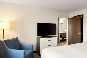 楠帕Everhome Suites Nampa Boise的酒店客房带一张床、一台电视和一把椅子