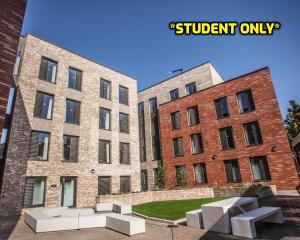 科尔切斯特Student Only Zeni Ensuite Rooms, Colchester的两座砖砌建筑,前面有白色长椅