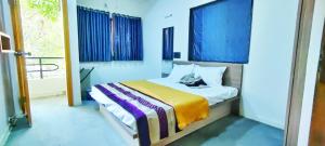 纳西克TULSI VILLA- The Holiday Home的一间卧室配有一张蓝色墙壁的床和一扇窗户
