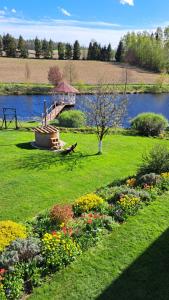 BorowinaDolina Miodu - Kaszuby, Sauna, Gorąca Balia的一座花园,花园内有一座桥,横跨一条鲜花盛开的河流