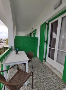 皮索利瓦迪Paradise Garden Paros的阳台设有绿门,配有桌椅