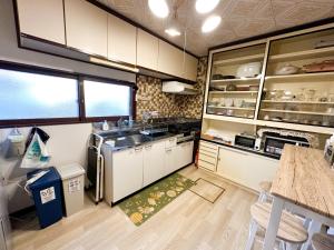 白老町Chano Onsen House 温泉付き的厨房配有白色橱柜、水槽和桌子