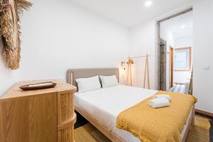 波尔图GuestReady - Bright Duplex in Downtown的一间卧室配有一张床和一张桌子,上面配有毛巾