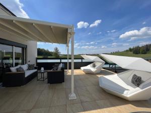 瓦瑟堡Poolhaus Bodensee ideal für Geschäftsreisende的屋顶上带白色沙发和椅子的庭院