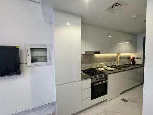 迪拜Furnished studio استديو مفروش studio city的厨房配有白色橱柜和炉灶烤箱。