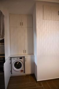 萨摩斯Passatempo Apartment Ireon的厨房配有洗衣机和烘干机,厨房配有白色橱柜
