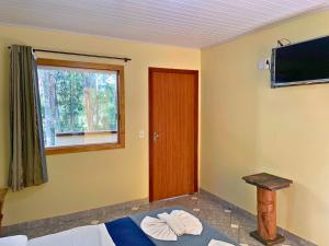 马卡科斯Pousada Casinha Velha的客房设有床、窗户和电视。