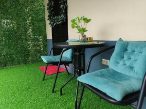 LocsinCasita de Reina Staycation House - A cozy 1-Bedroom condo-style house的一张桌子、两把椅子和一张桌子,铺着绿色地毯