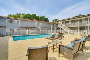 比洛克西Airy Biloxi Condo with Patio Walk to Beach!的一座带椅子的庭院和一座位于大楼前的游泳池