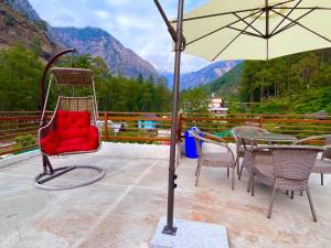卡索尔Hotel New Panchali With Mountain view By Winterline, Kasol的一把红色椅子,坐在桌子上,带雨伞