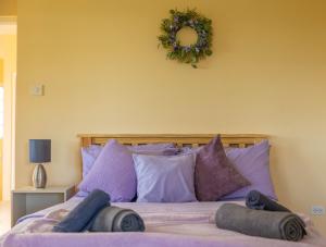 Arnos ValePierocks Highgate Entire house Free Parking and WI-FI的一张带紫色枕头的床和墙上的花圈