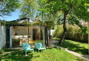 阿维尼翁Le mazet des amants, cabane en bois avec jacuzzi privatif的院子里的一栋带蓝色椅子的小房子