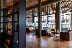 利物浦利物浦泰坦尼克酒店的餐厅设有皮沙发、桌子和窗户