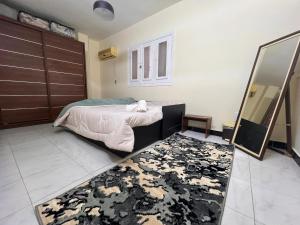 开罗Cairo's Heart Central Apartment in Masr El Gedida的一间卧室配有床、镜子和地毯