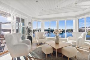 FoldnesWaterfront Villa w/Boat&kayaks. 15min from Bergen的客厅配有白色的椅子和桌子,窗户