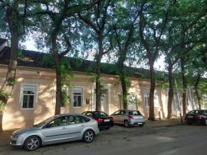 KikindaČudesni drvored的三辆汽车停在一座树木繁茂的建筑前