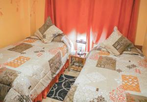 拉塔昆加Hotel Rodelu的配有红色窗帘的客房内的两张床