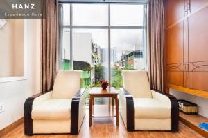 胡志明市HANZ Queen Airport Hotel的窗户客房内的两把椅子和一张桌子