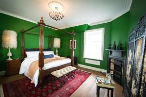 威廉堡Ardrhu House Fort William - Serviced Luxury Scots Baronial Country House的一间卧室设有绿色的墙壁、一张床和一个吊灯。