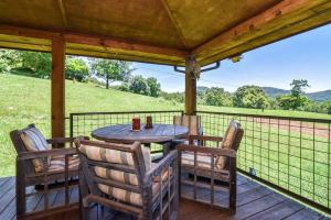 韦恩斯维尔Appalachian Farmhouse- A Homestead Experience的享有田野景致的门廊上的桌椅
