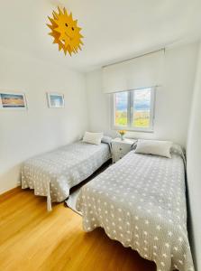 拉雷多APARTAMENTO el PUNTAL- LAREDO的配有白色墙壁和木地板的客房内的两张床