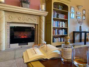 Cabezón de LiébanaHotel Finca Malvasia的一本书和一瓶威士忌放在餐桌上,餐桌上设有壁炉